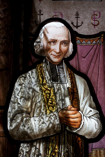 São João Maria Vianney com vestes sacerdotais e mãos em oração, trajando estola dourada.